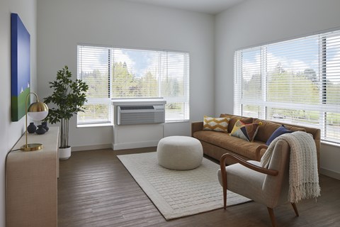 A living room with a brown couch and a white ottoman.